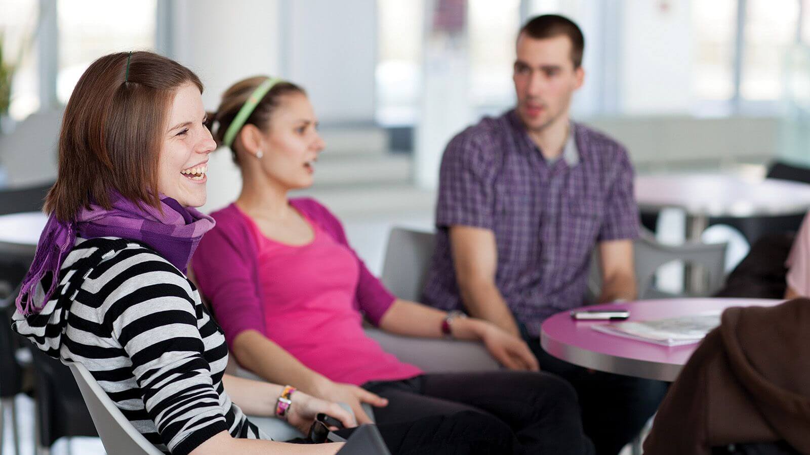 2 women and a man sitting and talking together